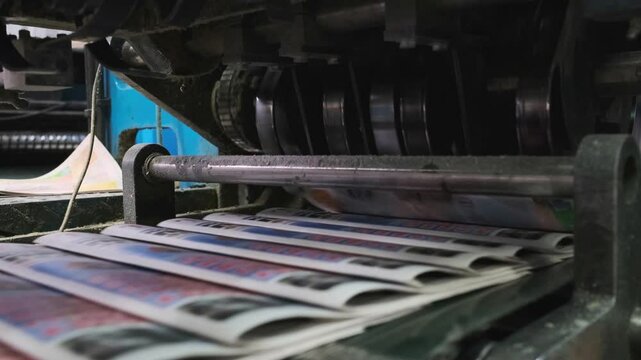 Industrial printing press operating in a printing house, efficiently producing and sorting newspapers for distribution. The machinery showcases modern printing technology in action.