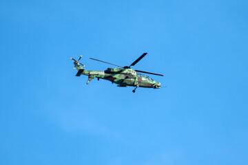 Helicopter is flying on isolated blue sky in mid-air background.