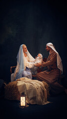 Fototapeta premium Holy and magical nativity scene with Mary gently holding baby Jesus with wise man, Joseph and shepherd standing around. Concept of Christmas, nativity scene, history, religion