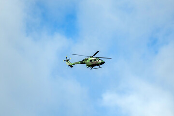 Helicopter is flying on isolated blue sky in mid-air background.