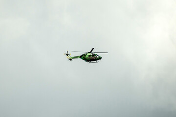 Helicopter is flying against isolated overcast dark blue sky