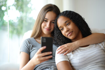 Relaxed interracial lesbian couple checking phone at home