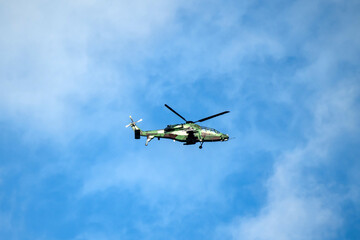 Helicopter is flying on isolated blue sky in mid-air background.
