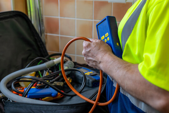 Gas Service Engineer wearing yellow high viz vest holding digital differential manometer pressure meter with open tool bag on domestic counter top