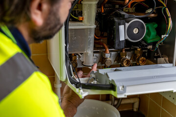 Gas service engineer applying silicone grease with finger to o-ring on part of domestic gas boiler