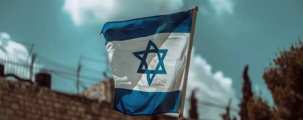 The image captures the Israeli flag waving proudly in front of a historic stone building.
