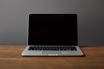 A sleek, modern laptop rests on a wooden surface, representing the emptiness before the journey of learning begins.