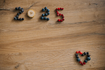 Fresh fruit arrangement forming the number 2025 in a heart shape on a wooden table