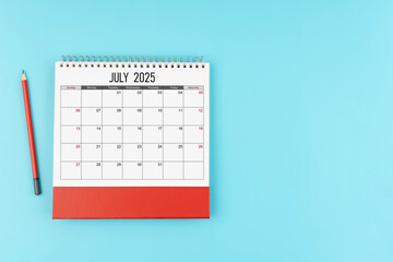 July desk calendar for 2025 year with pencil on blue background, Position with copy space.