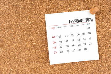 White calendar sheet for February 2025 with thumbtack on wooden board, Position with copy space.