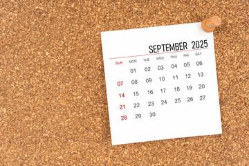 White calendar sheet for September 2025 with thumbtack on wooden board, Position with copy space.