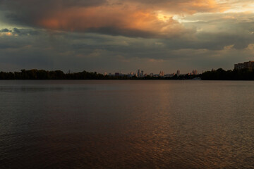 Bright sunset over lake, golden clouds reflect in the water