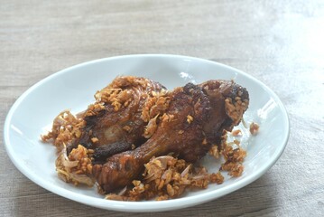 deep fried chicken tight and legwith pepper dressing crispy fried garlic on plate