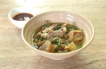 boiled braised beef meat and tendon in herb brown soup on bowl dipping spicy chili sauce 