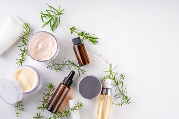 Clean beauty, eco organic natural cosmetics. Set of various cream, serum, moisturizing skincare cosmetics with green herbal leaves and sprigs, on white background copy space