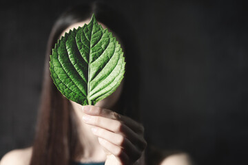 close-up of a leaf hides a woman's identity, abstract concept