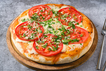 Neapolitan Margherita pizza with tomatoes, mozzarella, basil and olives on stone table