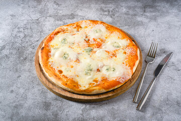 Four cheese neapolitan pizza on wooden cutting board on stone table