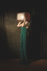 surreal woman covers her face with a television, abstract concept