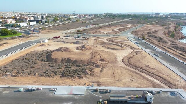 Drone captures an extensive aerial view of the entire new development project in Playa Flamenca, featuring road constructions, lorries, and early infrastructure setups