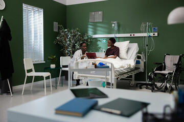 African patient signs papers with the doctor in the hospital.