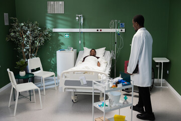 Hospital scene African patient in hospital bed African doctor stands beside with folder in hand checks symptoms.