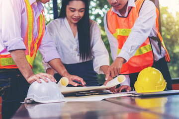 Structural engineer and architect and foreman worker with blueprints discuss, plan working for the building construction site office. Construction collaboration concept