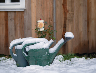 Im Garten liegt Schnee auf den Gießkannen 