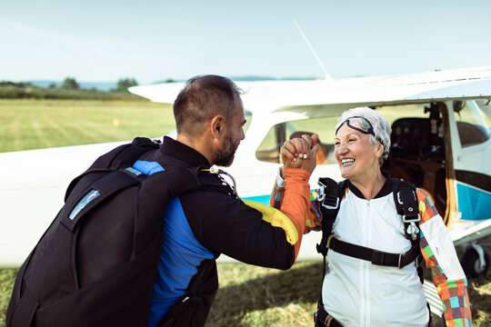 Senior woman high fiving instructor after successful skydive landing