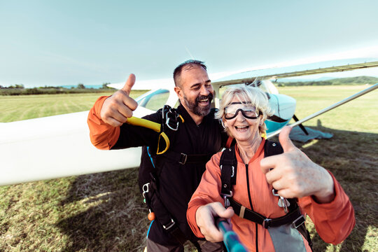 Happy senior woman and instructor taking selfie before skydiving
