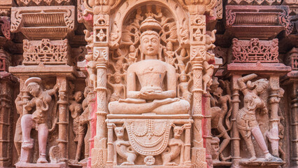 Ornate intricate carving of buddha surrounded by devotees in indian temple, unesco world heritage site, india