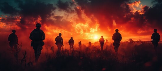Fototapeta premium Silhouettes of soldiers marching towards a fiery sunset.