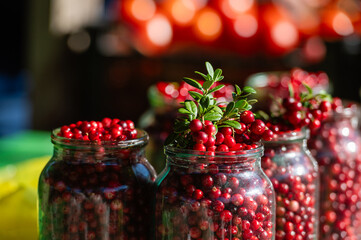 Freshly harvested red berries in glass jars at a vibrant farmers market during autumn
