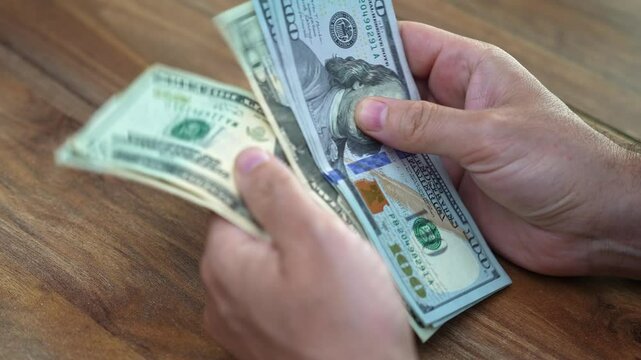 Male financial planner counts dollar bills to organize clients emergency cash fund providing peace of mind in case of unexpected financial needs during month