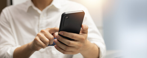 close up man hand hold mobile cell phone device to play social media or read news website on smartphone concept