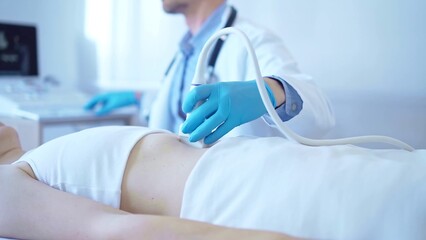 Doctor man wearing a blue medical gloves using an ultrasound equipment on a female patient lying...