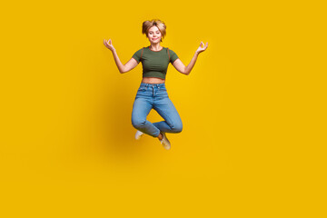 Obraz premium Full size photo of nice peaceful girl dressed khaki crop top jeans levitating in meditation pose isolated on yellow color background