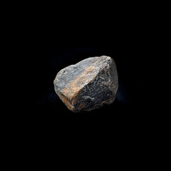 Single rugged rock illuminated against a black background, showcasing raw nature beauty.