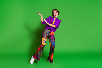 Photo of young woman in purple stylish shirt trendy vintage pants and brown bob haircut dancing discotheque isolated on green color background