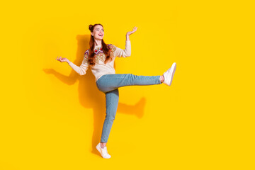 Photo portrait of attractive young woman dancing have fun dressed stylish knitted warm outfit isolated on yellow color background