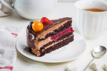 Delicate and delicious chocolate cake with butter cream and berries on a white table