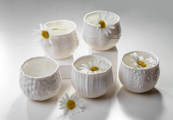 Porcelain white cups with chamomile flowers on a light table