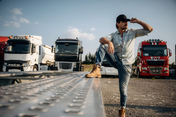 Foot is on the trailer. Truck driver is near the transport outdoors