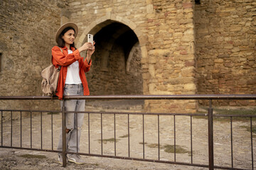 Female traveler photographing ancient fortress during solo exploration