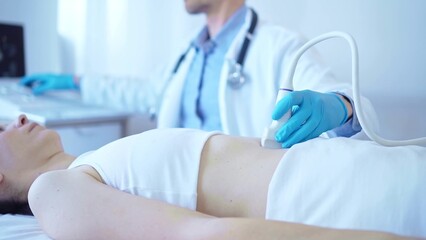 Doctor man wearing a blue medical gloves using an ultrasound equipment on a female patient lying down in clinic cabinet. Medicine concept