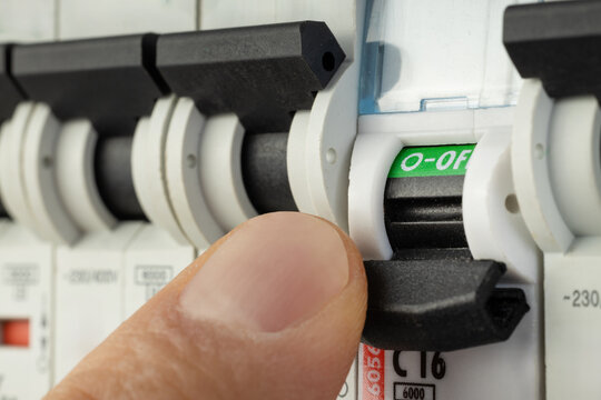Hand flipping electrical switch in breaker panel