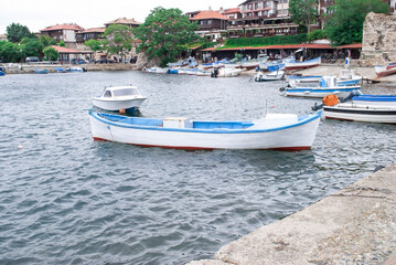 Fototapeta premium Boats mooring on sea in Nessebar, Bulgaria. Summer landscape with moored woods boat at quay by blue sky