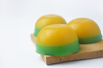 Yellow green round layered cake on a wooden coaster is an Indonesian food
