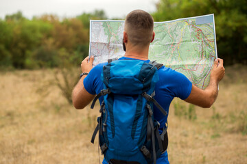 Young male hiker checking map, travel vacations concept