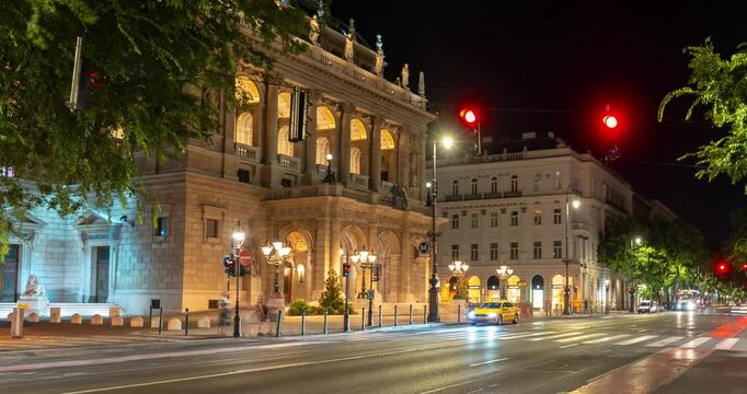 Budapest, Hungary - August 10, 2024: Cars traffic near Budapest's opera building at night. Time-lapse, zoom-out transition.